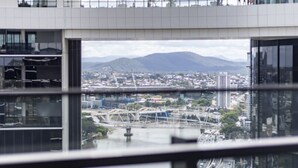 Un edificio moderno con grandes ventanales y vistas a un paisaje urbano y montañas al fondo.