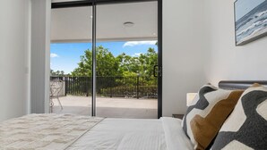 Un dormitorio con cama, vistas al exterior y un cuadro en la pared.