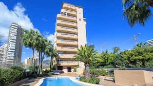 A hotel with a swimming pool, palm trees, and a view of other buildings. - Apartment Oasis by Interhome (Calpe/Calp)