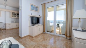 A hotel room with a TV, a dining area, a sofa, and a view of the sea. - Apartment Oasis by Interhome (Calpe/Calp)