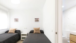 A bedroom with two beds, a nightstand, and a small table. There are two motivational posters on the wall.