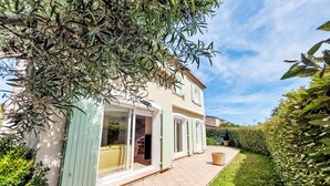 Una casa de dos pisos con un patio, una puerta de cristal y un jardín bien cuidado.