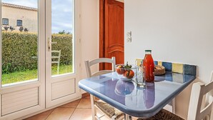 Un comedor con una mesa, sillas y vistas al jardín a través de un ventanal.