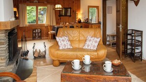 A cozy living room with a leather sofa, a fireplace, and a dining area with wooden furniture.