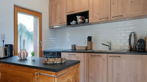 A modern kitchen with wooden cabinets, a black countertop, and a built-in stove.