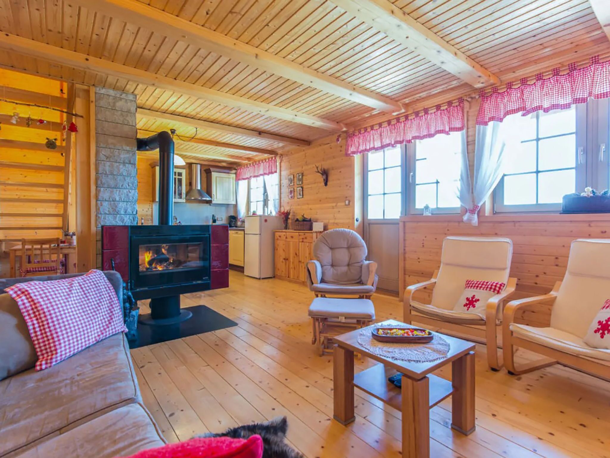 A cozy cabin interior with a fireplace, wooden furniture, and a stone wall.