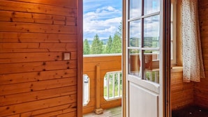A wooden cabin with a large window and a view of a forest.