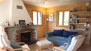 Un salón acogedor con chimenea, un sofá y dos sillones.