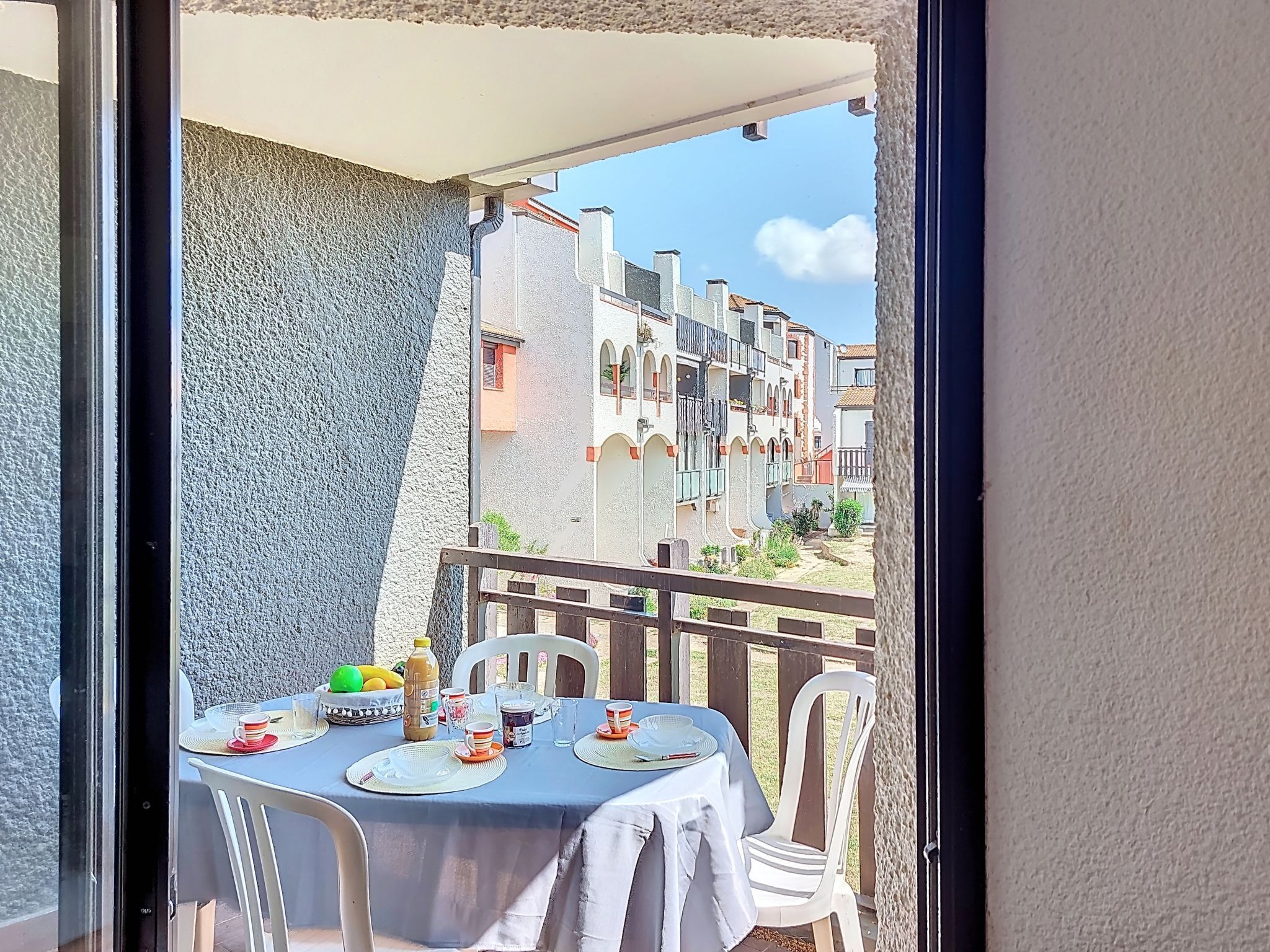 Ein Balkon mit Esstisch, der auf eine Reihe von Gebäuden mit Balkonen blickt.
