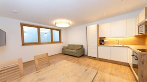 A modern kitchen with white cabinets, a wooden dining table, and a sofa. - Apartment in Kleinarl near Ski Slopes (Kleinarl)
