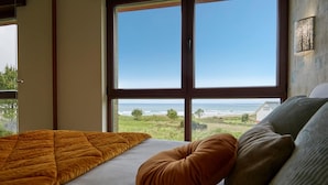 Un dormitorio con un ventanal que ofrece vistas al océano y a la playa.