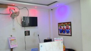 Een receptiehal met een marmeren vloer, een receptiebalie, een aan de muur bevestigde televisie en een bord met daarop de uitchecktijden.