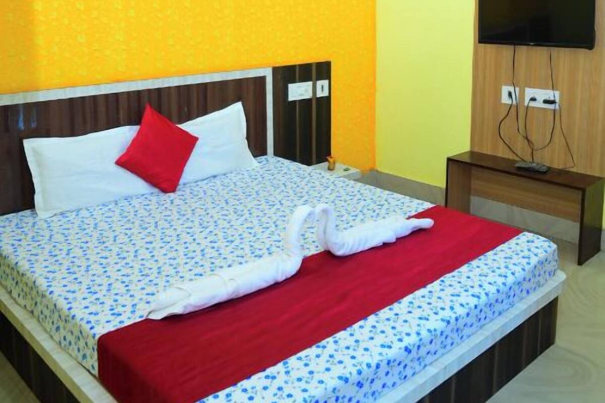 Une chambre d’hôtel avec un lit, une télévision et un ventilateur de plafond.