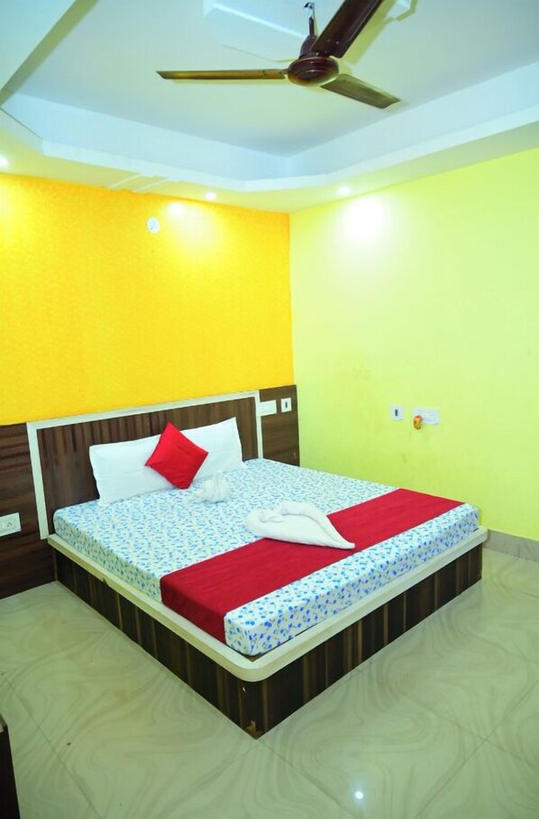 A hotel room with a bed, a ceiling fan, and a light switch on the wall.