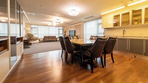 A modern living room with a dining area, wooden flooring, and a kitchen with cabinets and a sink. - Available for up to 30 people 4-bedroom apartment in enchanting Busan with WiFi (Busan)