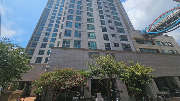 A tall, modern building with a prominent entrance and a pedestrian bridge. - Available for up to 30 people 4-bedroom apartment in enchanting Busan with WiFi (Busan)