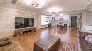 A spacious living room with a large flat-screen TV, a leather sofa, and a wooden coffee table. - Available for up to 30 people 4-bedroom apartment in enchanting Busan with WiFi (Busan)