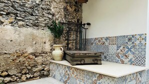 A stone wall, a tiled bench, and a potted plant in a courtyard.