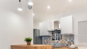 A modern kitchen with a wooden island, white cabinetry, and a patterned backsplash.