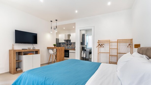 A modern bedroom with a large bed, a desk, and a TV.