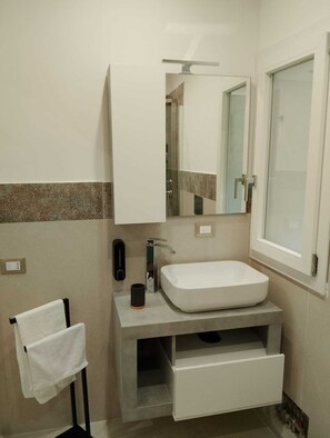 Ein modernes Badezimmer mit Waschbecken, Handtuchhalter, Spiegel und Fenster.