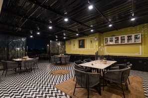 A restaurant interior with a checkered floor, multiple dining tables, and chairs. - Wanderlust – A Boutique Homestay (Udaipur)