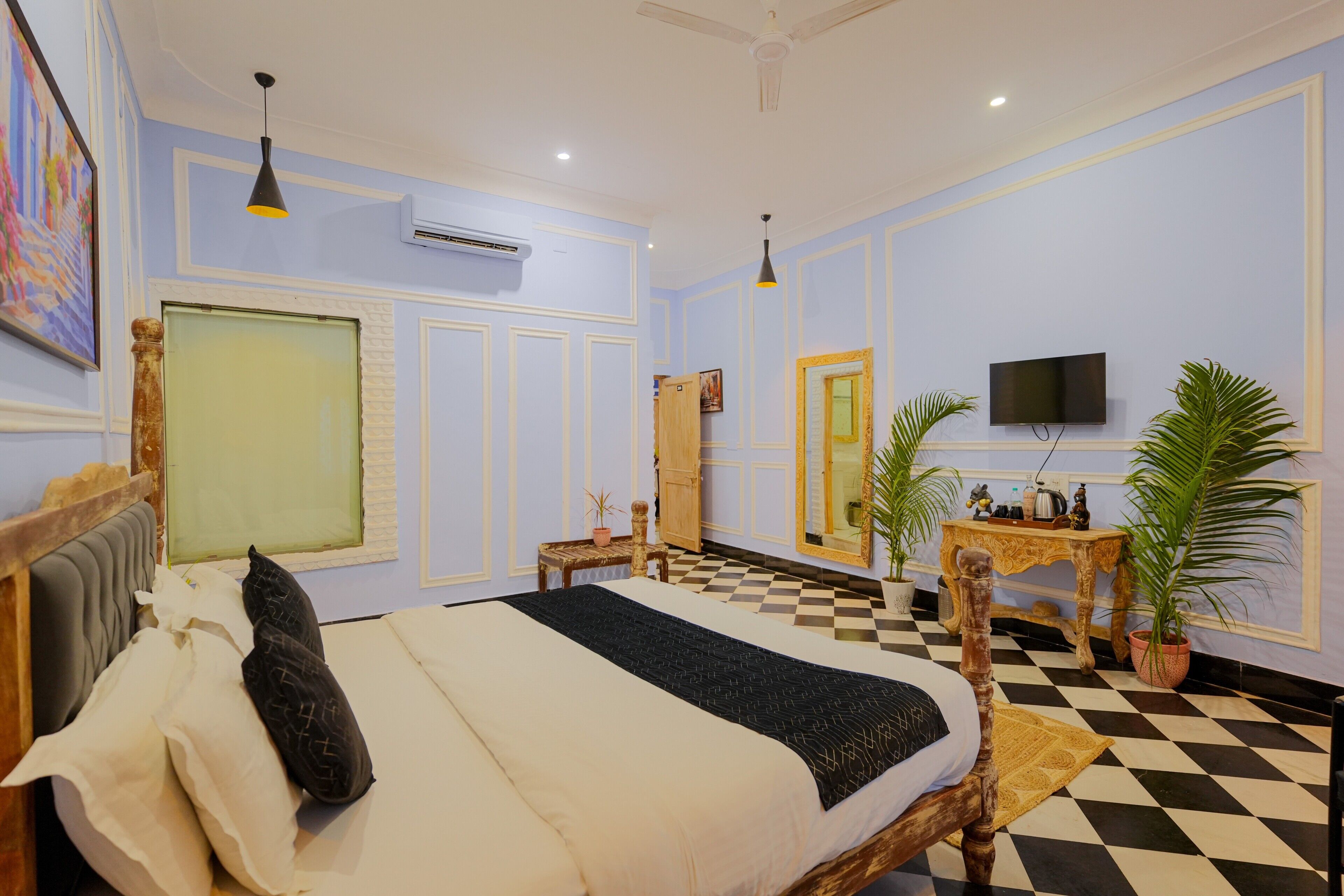 A hotel room with a bed, a television, a desk, and a checkered floor.