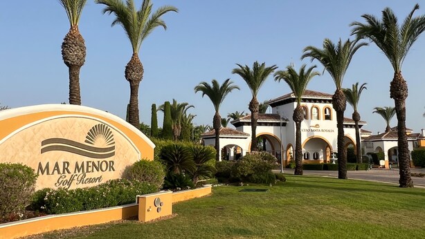Un panneau indiquant un complexe hôtelier avec un parcours de golf, agrémenté de palmiers et d’un bâtiment portant l’inscription « Mar Menor Golf Resort ».