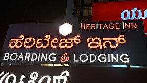 Een hotelschild met 'Heritage Inn' en 'Boarding & Lodging' in het Engels en een andere taal.