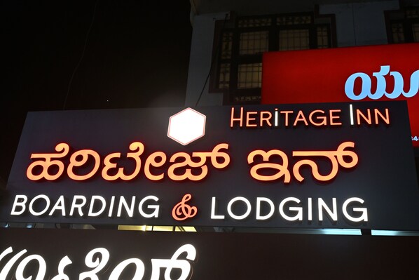 Une enseigne d’hôtel indiquant « Heritage Inn » et « Boarding & Lodging » en anglais et dans une autre langue.