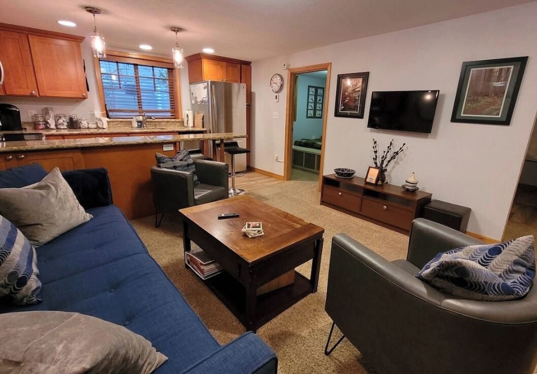 A living room with a blue sofa, a coffee table, and a TV mounted on the wall.