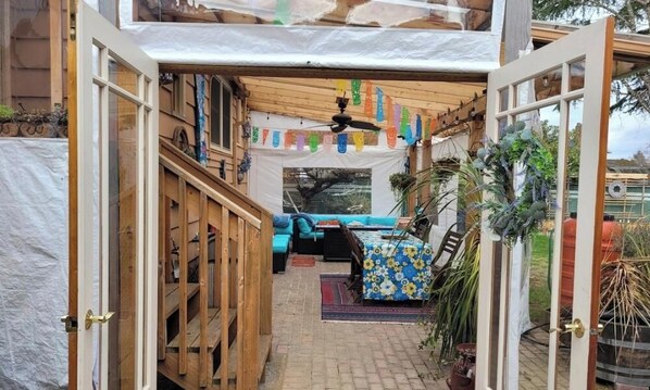 An open doorway leading to a cozy patio area with a bed, a ceiling fan, and a view of the outdoors. - Live like a local in Laurelhurst—family friendly (Portland)