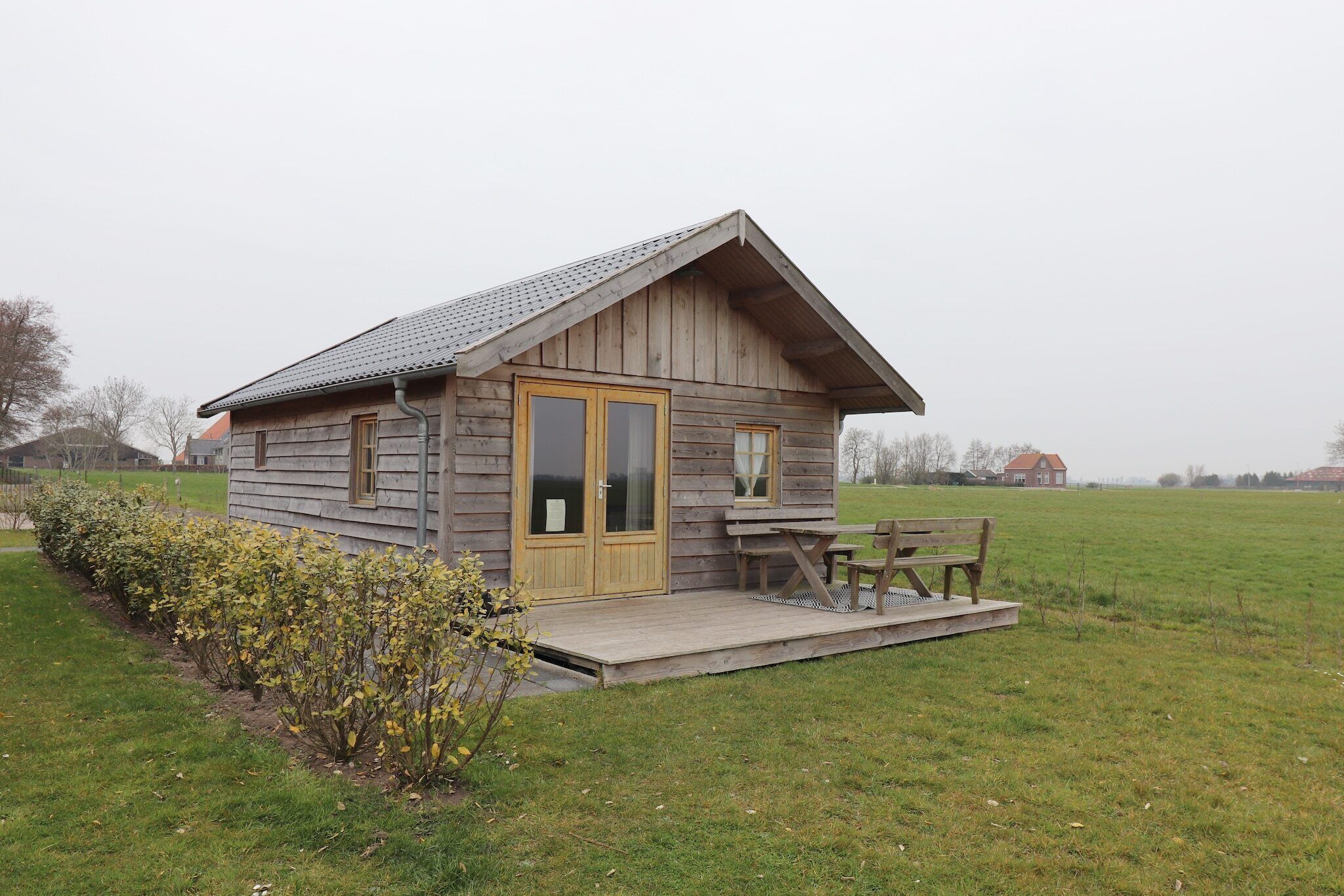 A wooden cabin with a porch, a bench, and a table.