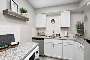 A compact kitchen with white cabinets, granite countertops, and a built-in dishwasher. - Stallion 2bedroom 1bath w/ Free Parking and Wi-Fi Peaceful and Clean Book now! (Lawrence)