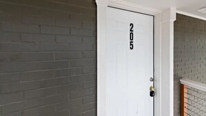 Una porta bianca con il numero 205, una serratura metallica e uno stipite bianco.