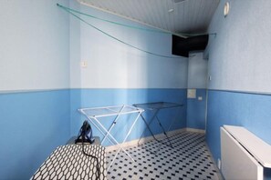 Una habitación pequeña con piso estampado, un tendedero metálico y un armario blanco.