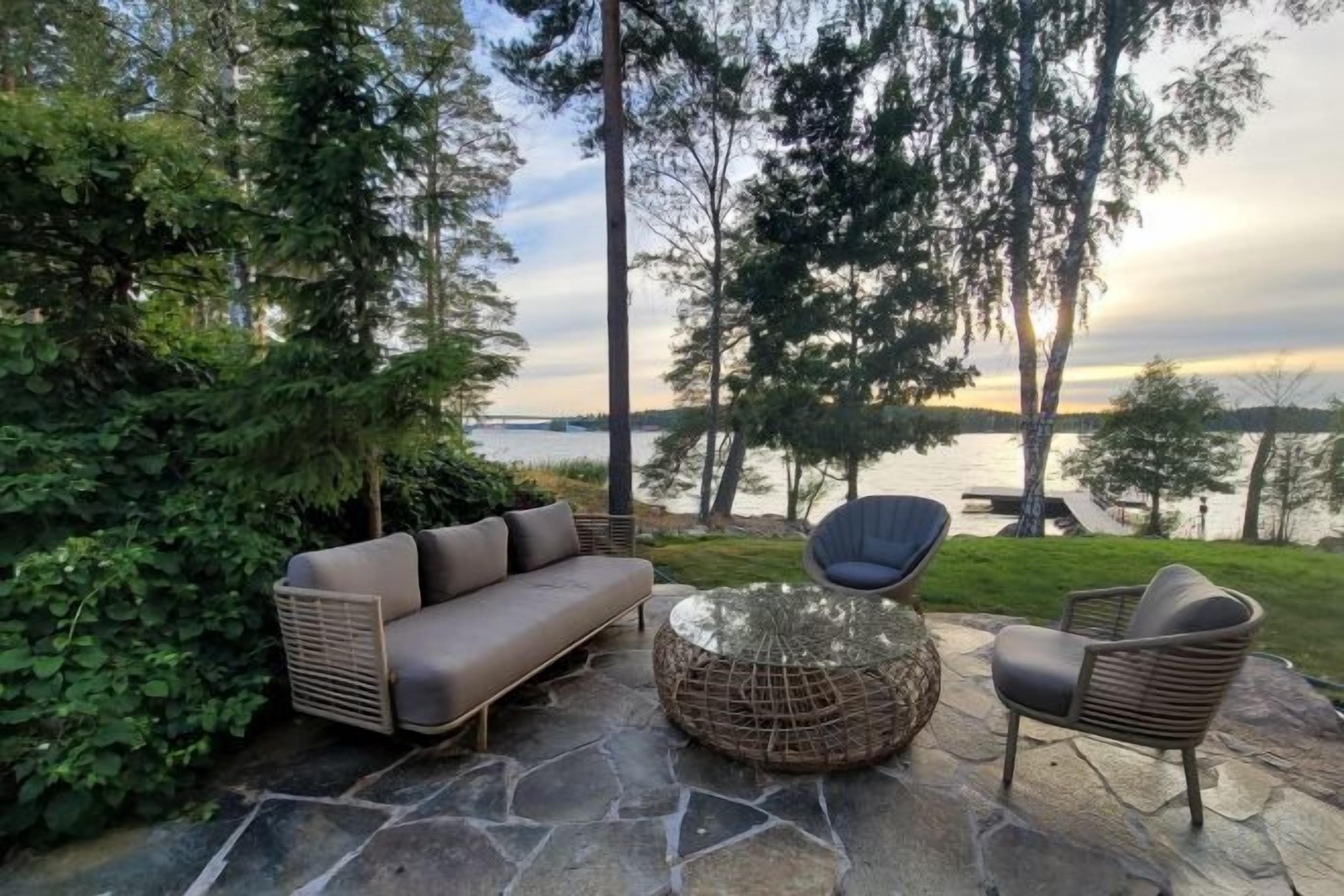 Un espace extérieur aménagé avec un canapé, des chaises et une table, offrant une vue sur une étendue d’eau.