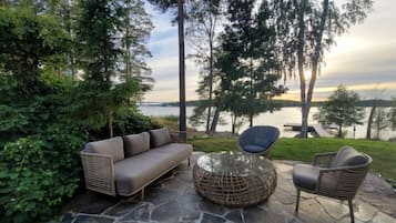 Un espace extérieur aménagé avec un canapé, des chaises et une table, offrant une vue sur une étendue d’eau.
