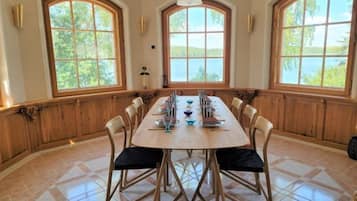 Un espace repas avec une longue table, des chaises et de grandes fenêtres.