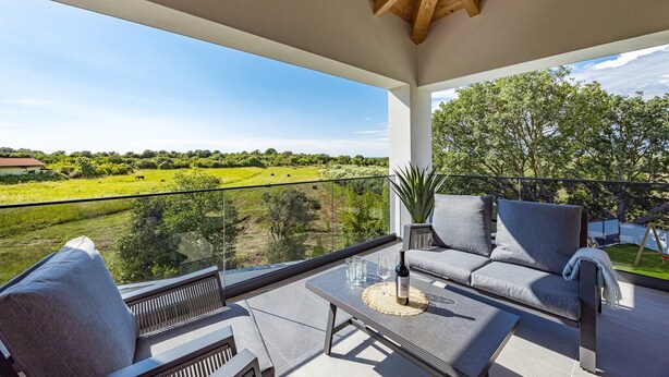 A balcony with a sofa, a table, and a bottle of wine. - Villa in Štinjan near Hidrobaza Beach (Štinjan)