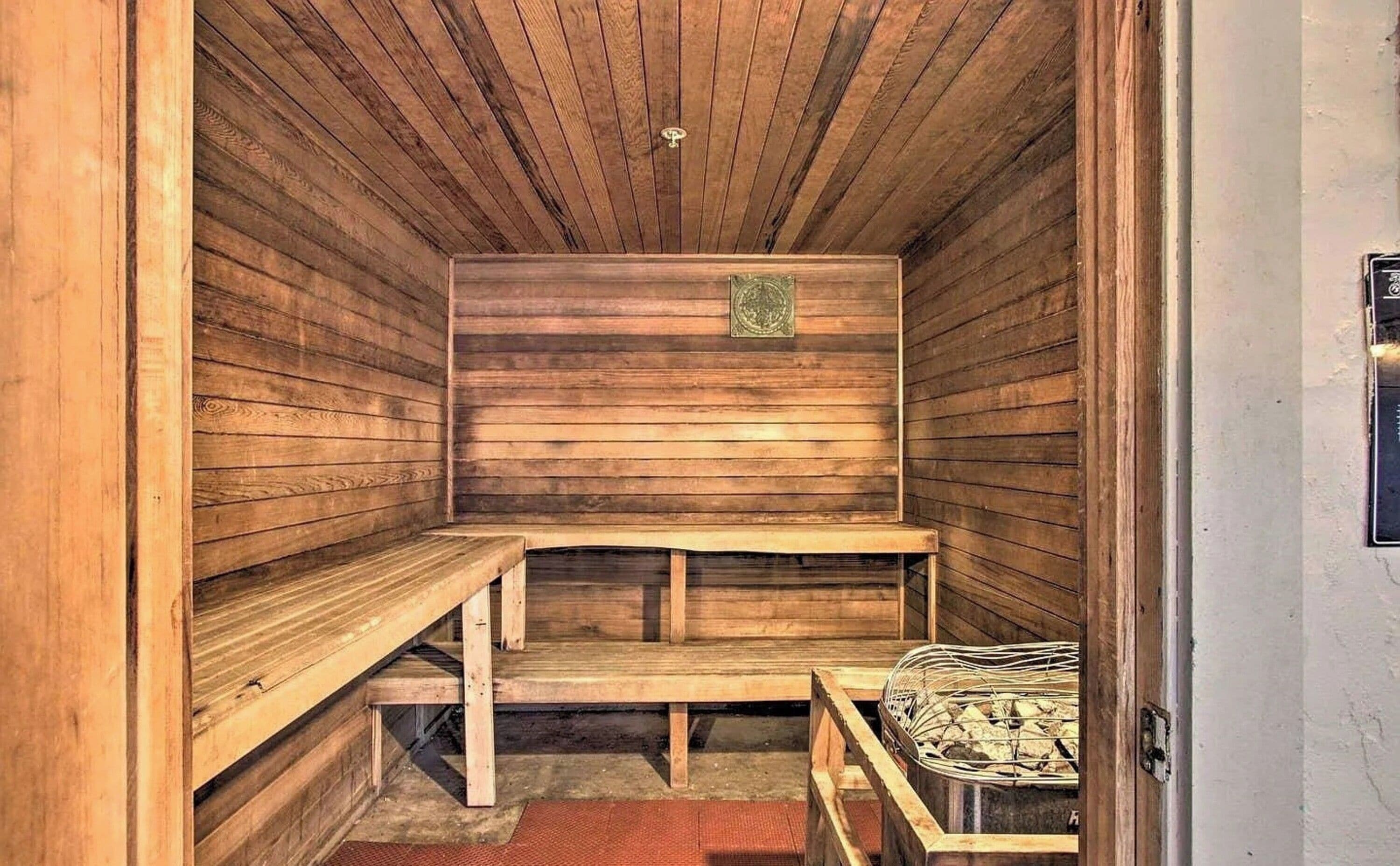 Una sauna con bancos de madera y un banco con asiento de mimbre.