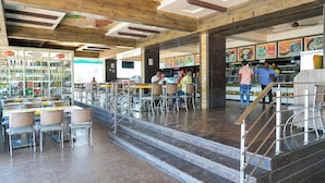 A spacious restaurant with high ceilings, exposed beams, and a variety of seating options. - Sri Krishna Inn (Devanahalli)