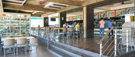 A spacious restaurant with high ceilings, exposed beams, and a variety of seating options.