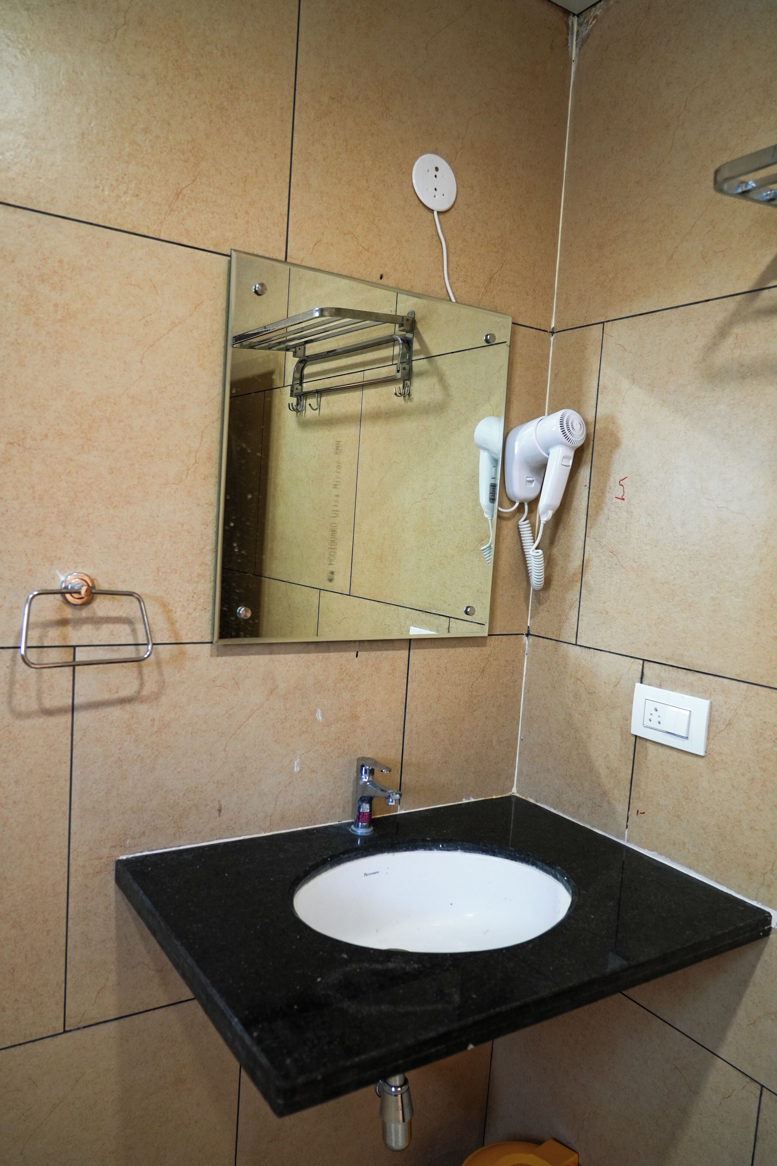 A bathroom with a black sink, a mirror, a hairdryer, and a towel rack.