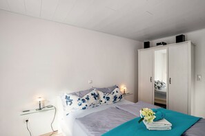 Un dormitorio con cama, armario, mesita de noche y lámpara.