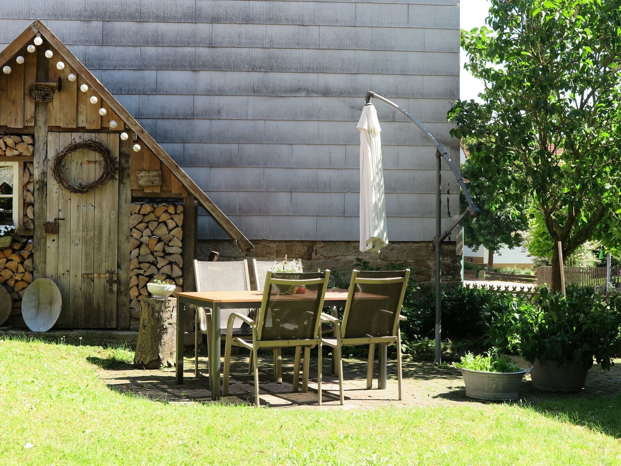Un espace extérieur rustique, aménagé avec une table et des chaises en bois, une lanterne et un mur en pierre.