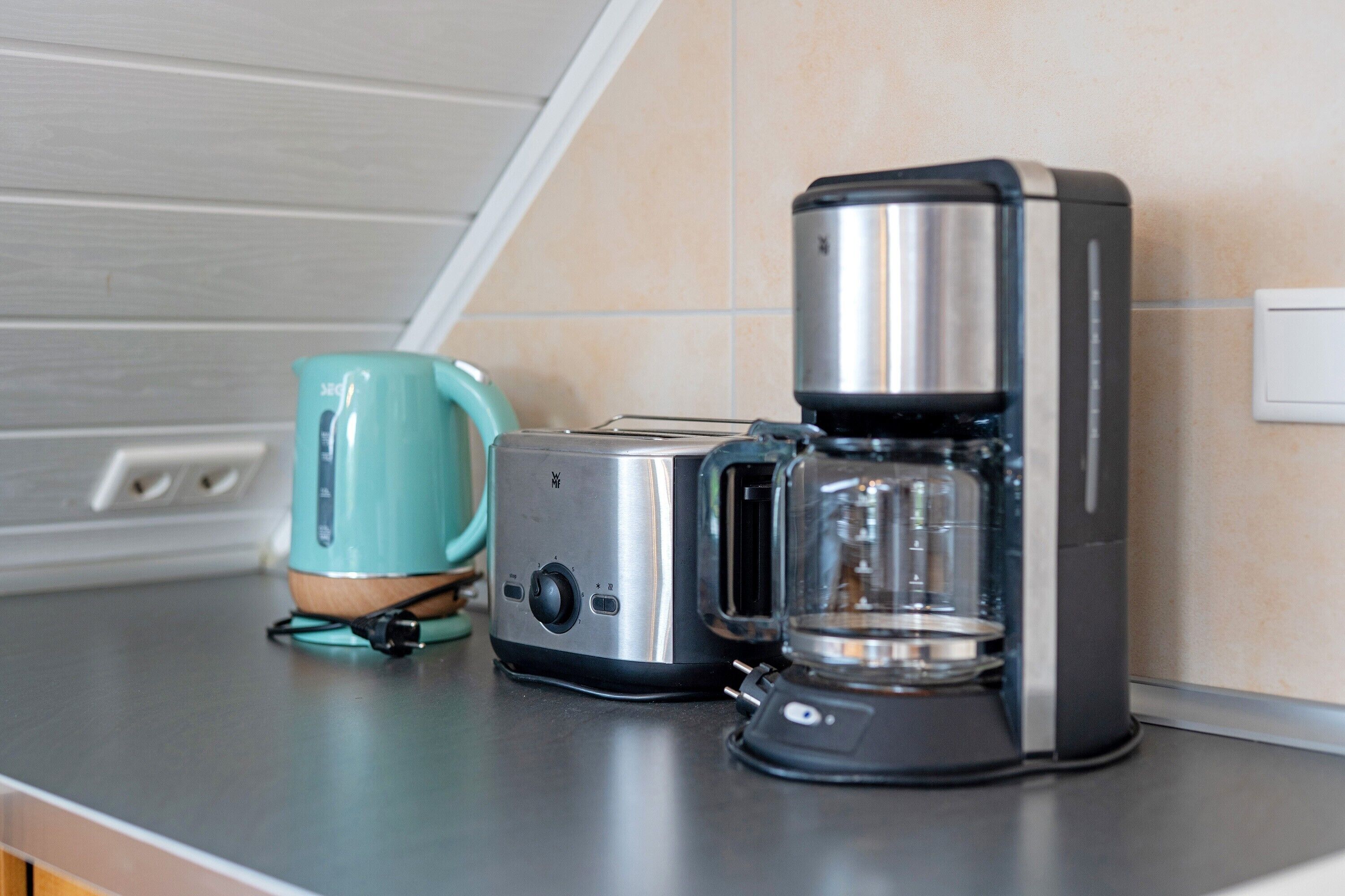 A kitchen with a toaster, a coffee maker, and a teal mug on the counter.
