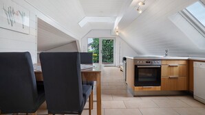 Une cuisine moderne avec un coin repas, des meubles en bois et une lucarne.