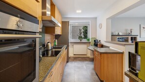 Une cuisine moderne avec des meubles en bois, des appareils électroménagers en acier inoxydable et une fenêtre donnant sur un paysage verdoyant.