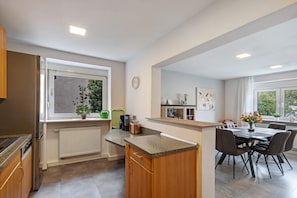 Una cocina moderna con horno empotrado, ventana con vistas y un comedor con mesa y sillas.